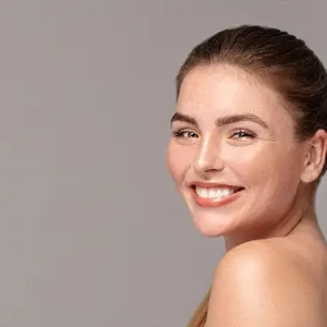 Beauty portrait of young attractive ginger woman with freckles on her face and body. Natural girl smiling to the camera. Studio shot.